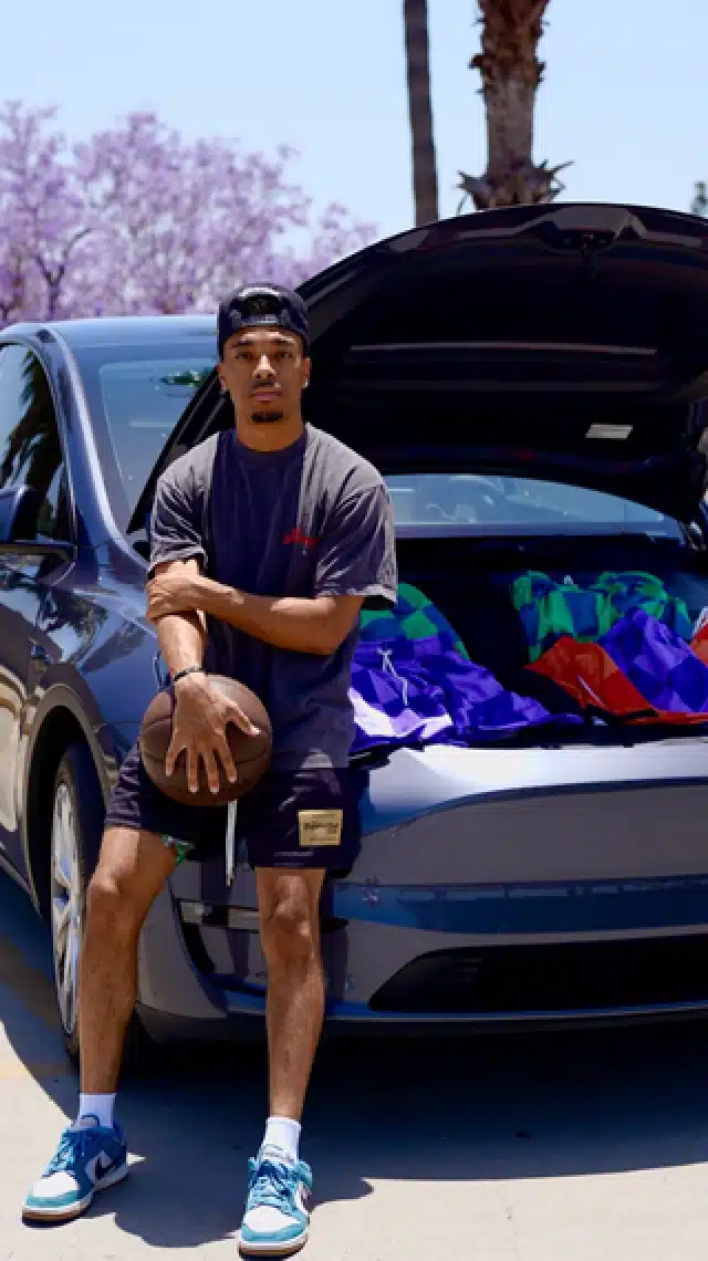 a man holding a basketball next to a car